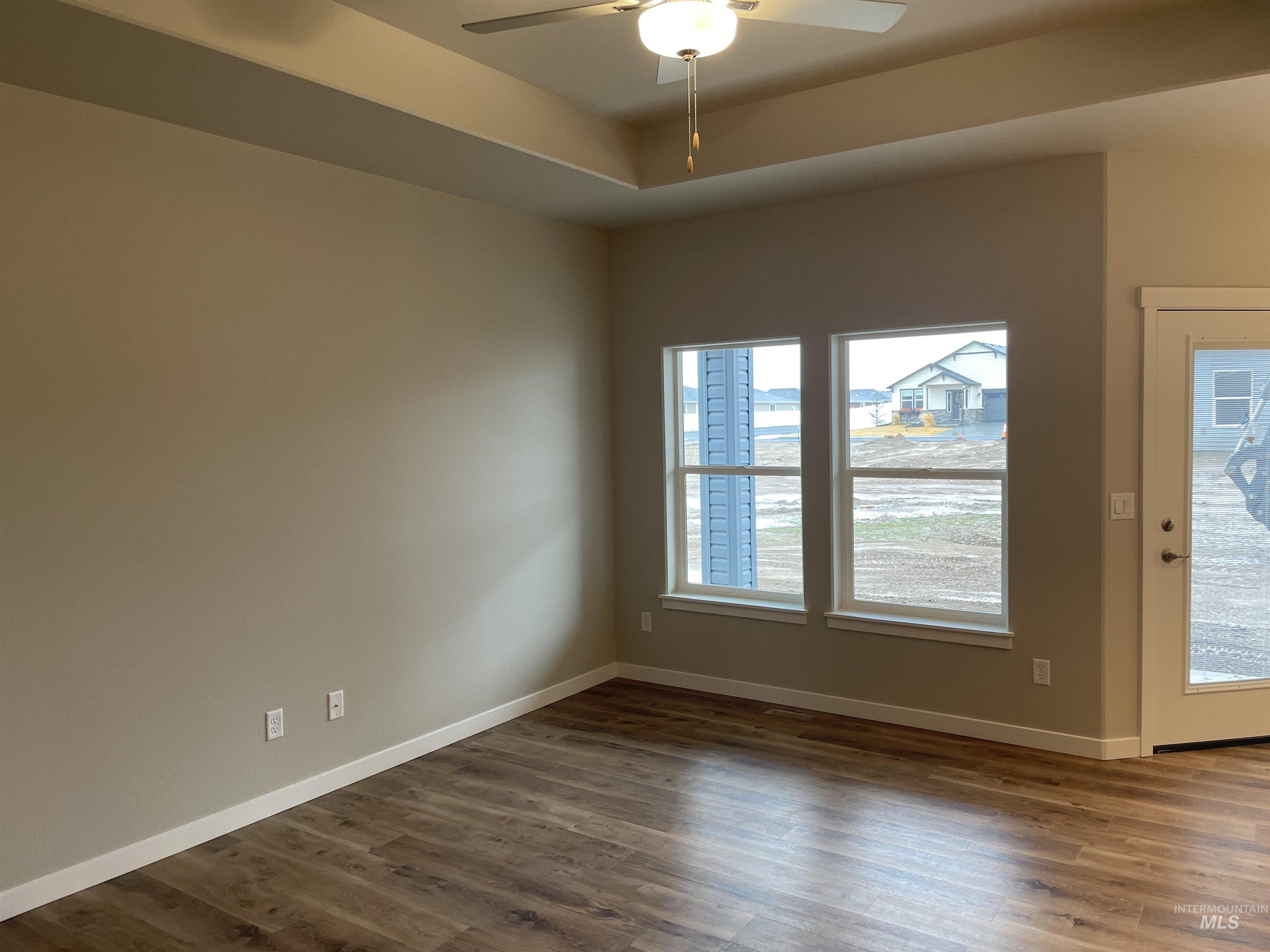 1123 Frank Henry Road Twin Falls, ID 83301 - Photo 4 of 20 Spare room featuring dark wood-style floors, a ceiling fan, and a tray ceiling