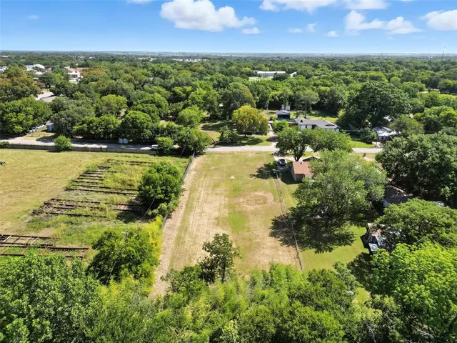an aerial view of residential houses with outdoor space and trees all around