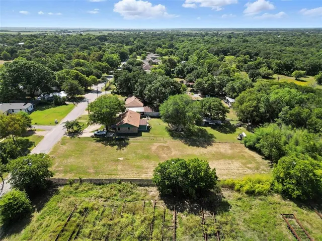 an aerial view of residential houses with outdoor space and trees