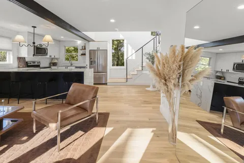 a living room with stainless steel appliances kitchen island granite countertop furniture and a rug