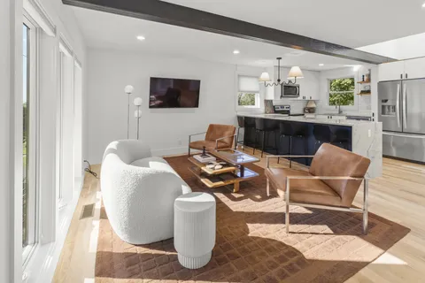 a living room with furniture a flat screen tv and kitchen view