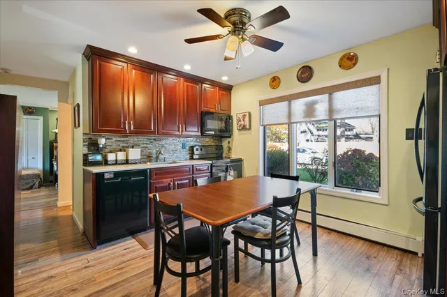 a kitchen with stainless steel appliances granite countertop a stove a refrigerator a microwave a dining table and chairs with wooden floor