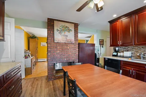 a kitchen with stainless steel appliances kitchen island granite countertop a stove top oven a sink dishwasher a dining table and chairs with wooden floor