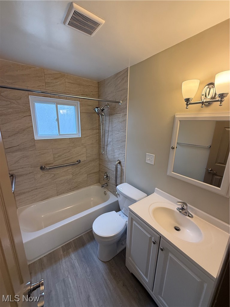 9417 Alexander Road Garfield Heights, OH 44125 - Photo 24 of 38 Bathroom featuring visible vents, shower / washtub combination, toilet, vanity, and wood finished floors