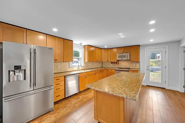 a large kitchen with stainless steel appliances granite countertop a sink and cabinets