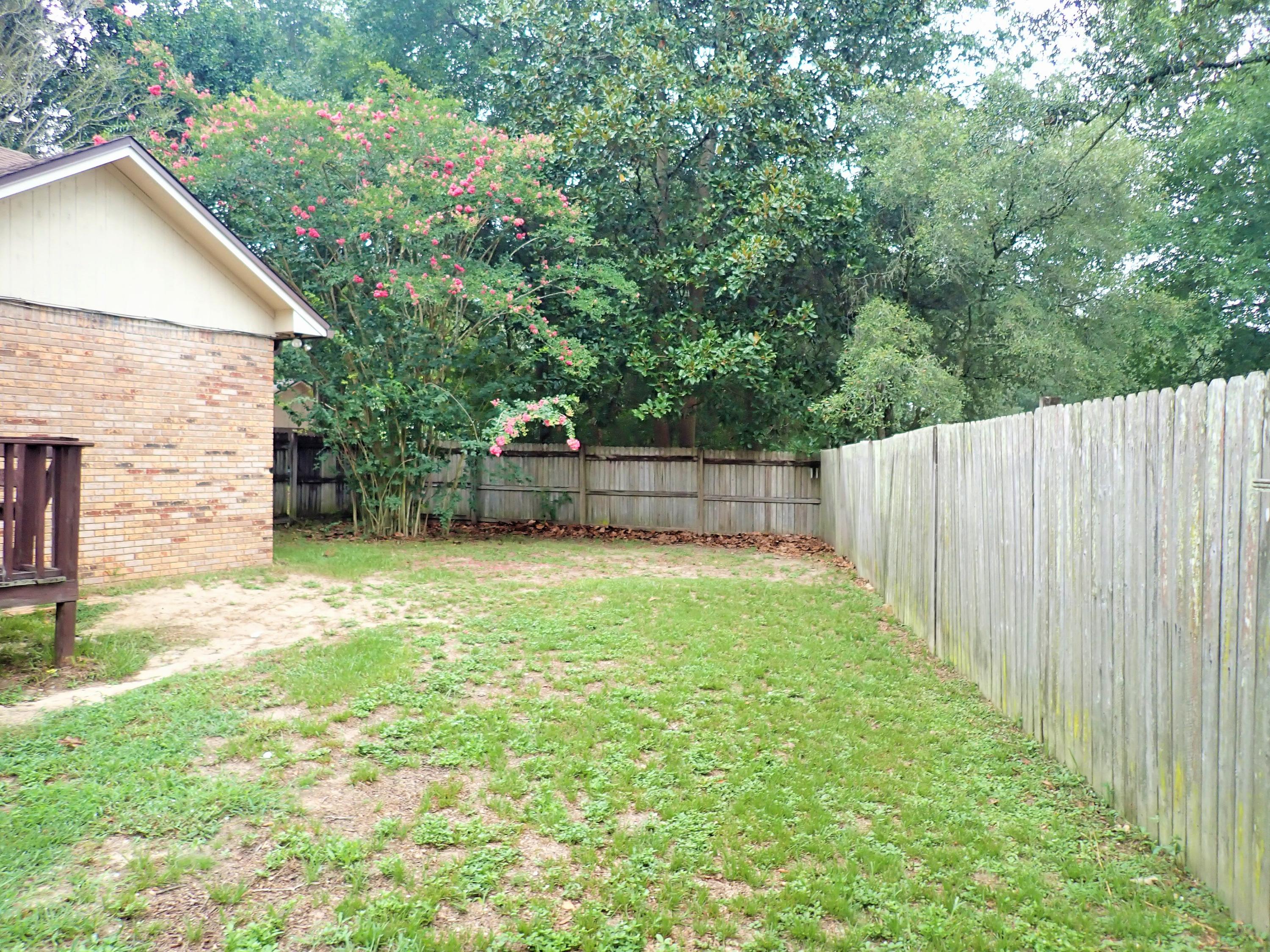 303 Sheldon Court Crestview, FL 32539 - Photo 38 of 45 a view of a backyard with a small cabin and a chair