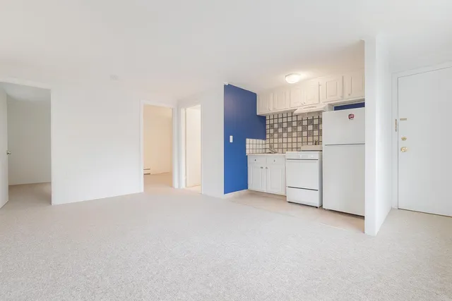 a kitchen with a refrigerator and white cabinets