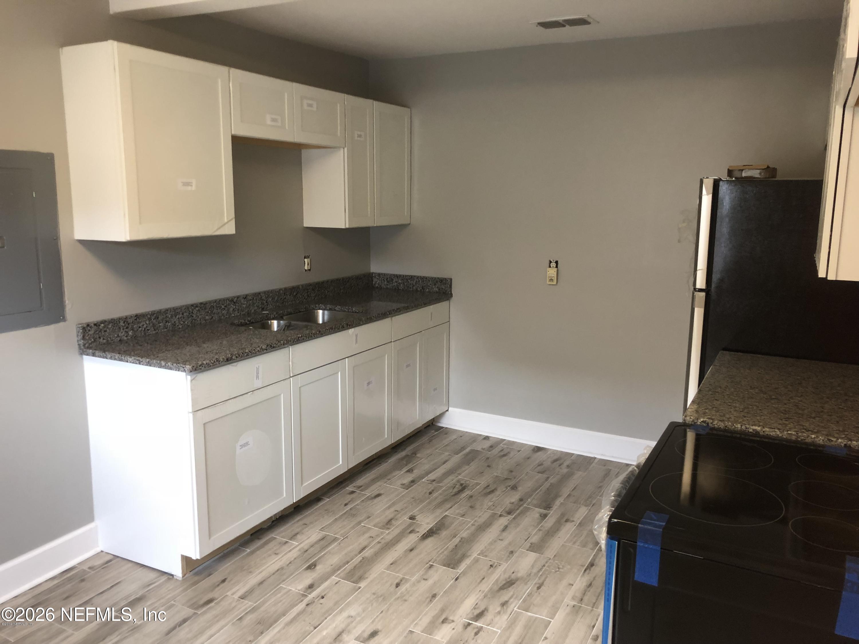 925 Phillips Street, Unit 3 Jacksonville, FL 32207 - Photo 2 of 10 a kitchen with granite countertop white cabinets and black appliances