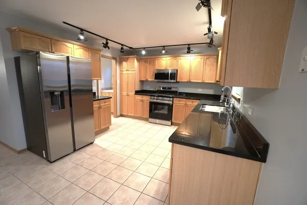 a kitchen with stainless steel appliances granite countertop a refrigerator a stove and a sink with wooden floors