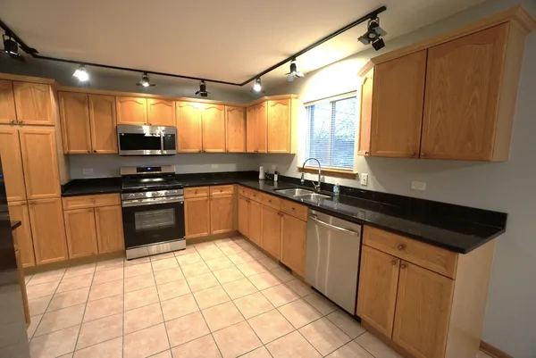 a kitchen with granite countertop a sink a counter top space cabinets and stainless steel appliances