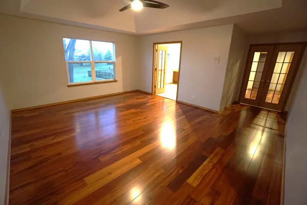 a view of an empty room with wooden floor and windows