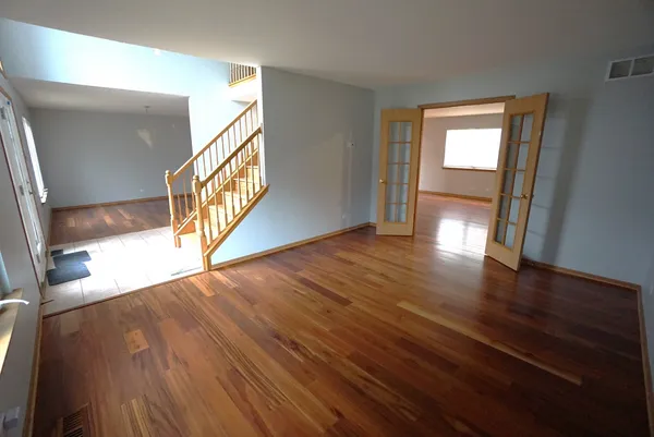 a view of an empty room with wooden floor and a window