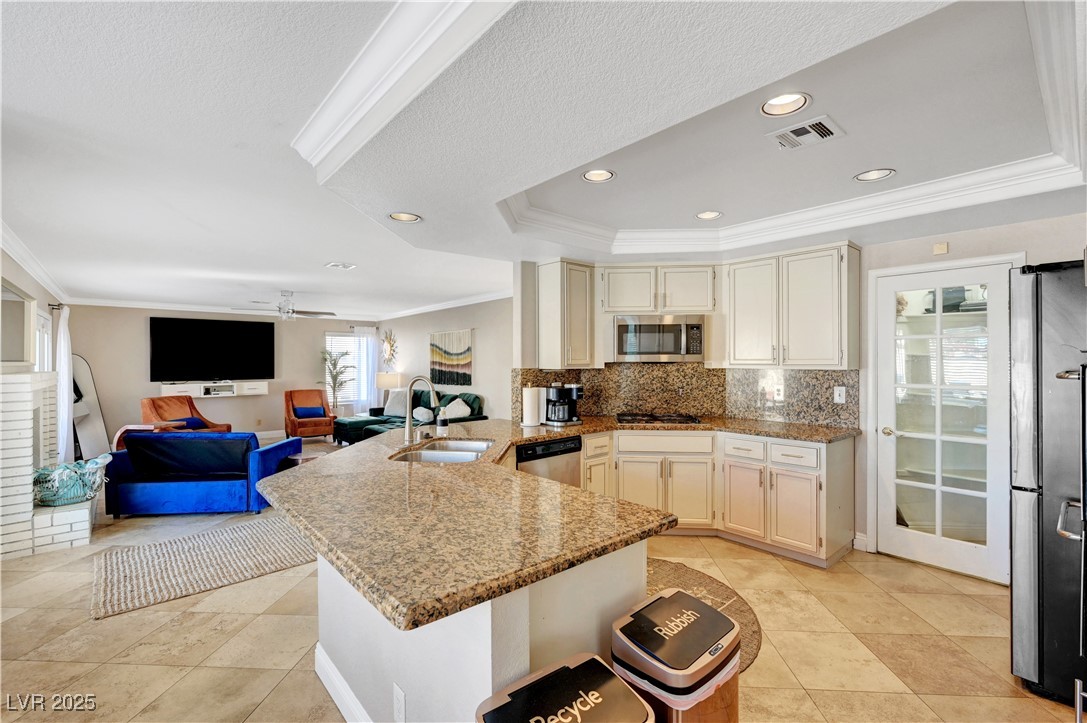 1486 Powder Horn Drive Henderson, NV 89014 - Photo 20 of 99 Kitchen featuring ornamental molding, light stone counters, a raised ceiling, a peninsula, and appliances with stainless steel finishes