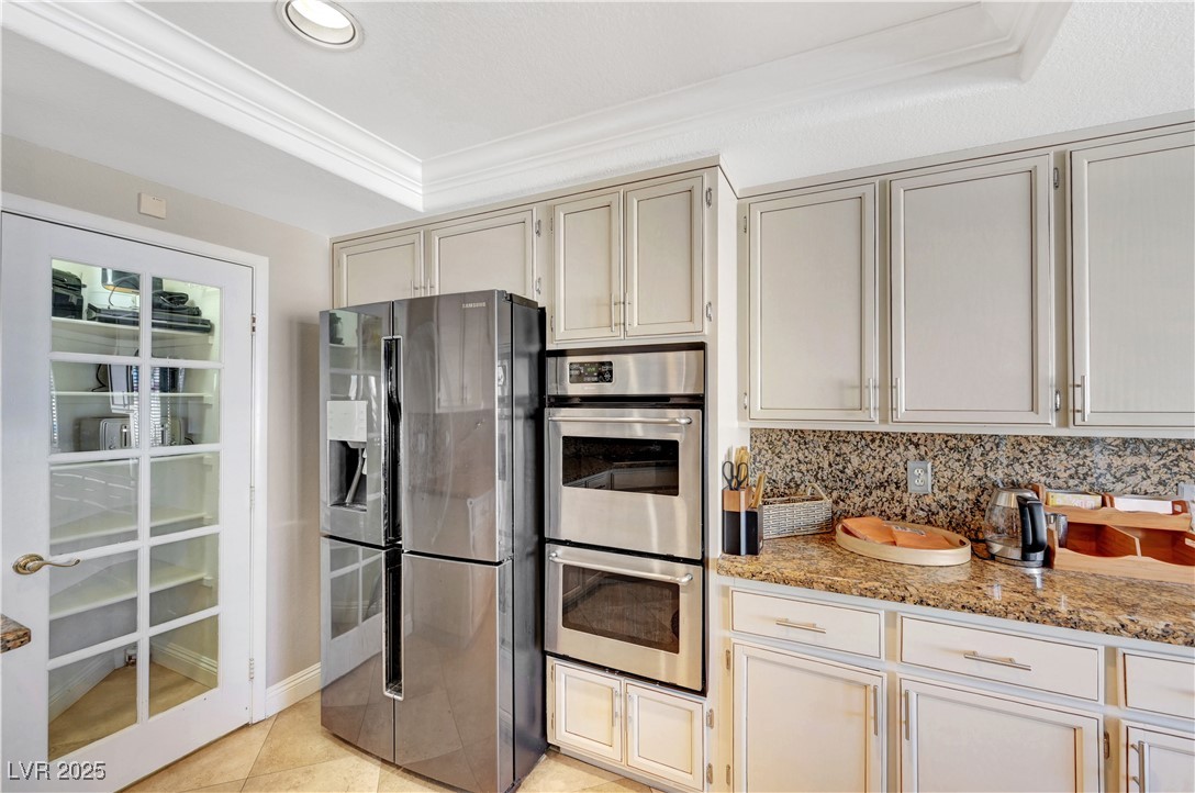 1486 Powder Horn Drive Henderson, NV 89014 - Photo 22 of 99 Kitchen with appliances with stainless steel finishes, backsplash, ornamental molding, light stone counters, and a raised ceiling