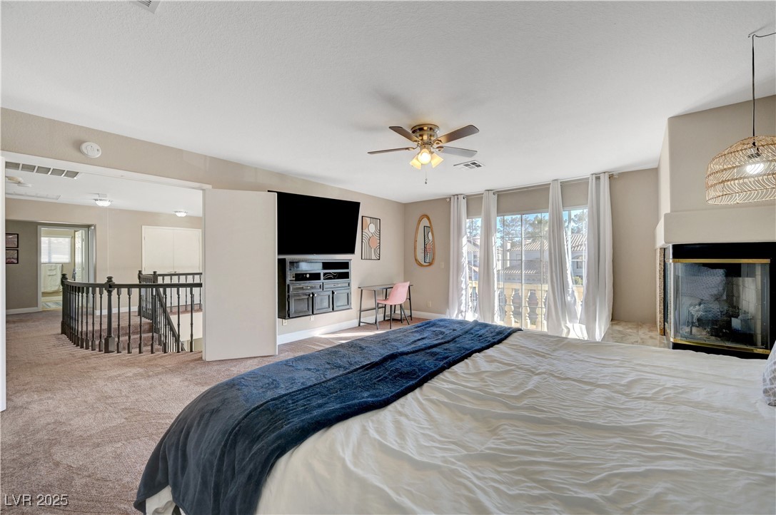 1486 Powder Horn Drive Henderson, NV 89014 - Photo 49 of 99 Bedroom featuring a multi sided fireplace, carpet, a ceiling fan, expansive windows, and access to outside