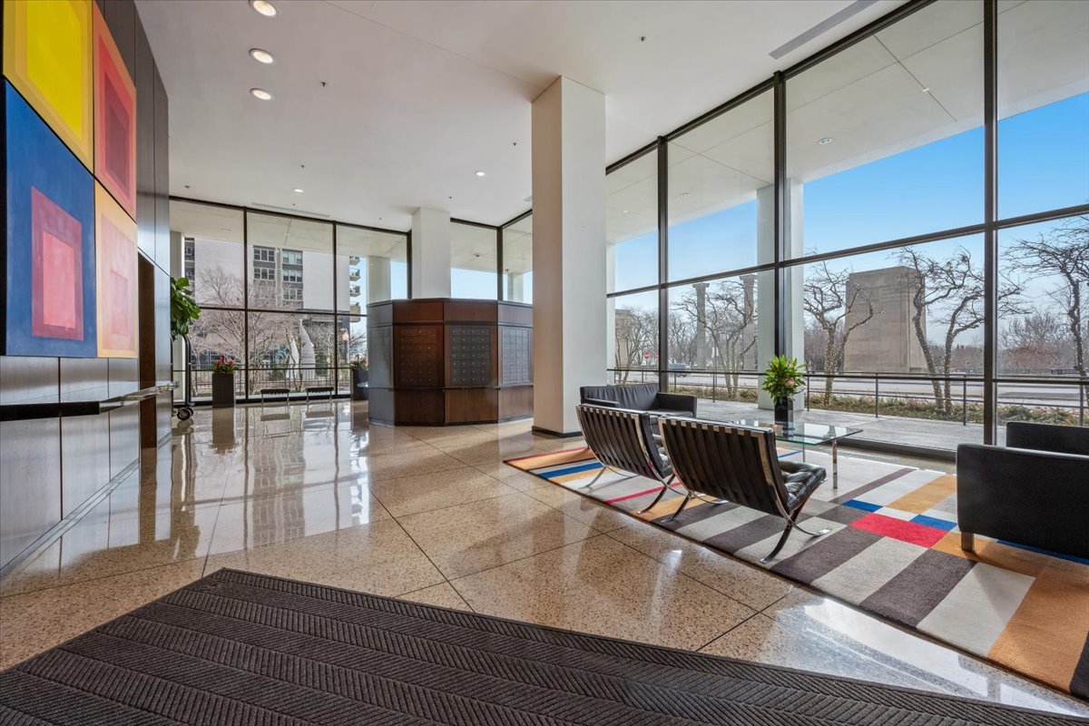 360 East Randolph Street, Unit 1002 Chicago, IL 60601 - Photo 2 of 27 a living room with furniture a flat screen tv and a floor to ceiling window
