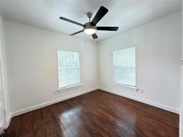 a view of empty room with wooden floor and fan