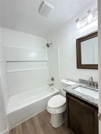 a bathroom with a granite countertop sink a toilet and bathtub