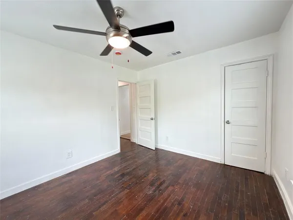 an empty room with wooden floor fan and windows