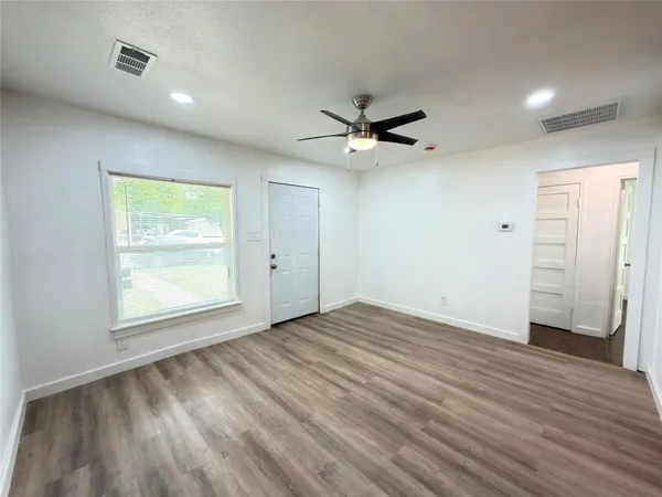an empty room with wooden floor and windows