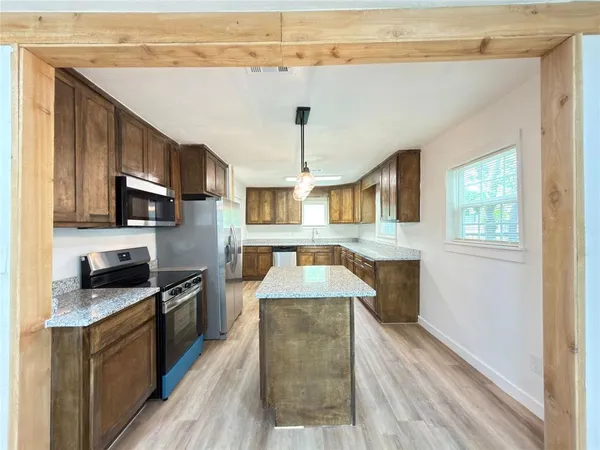 a kitchen with stainless steel appliances granite countertop wooden cabinets a stove top oven a sink and dishwasher