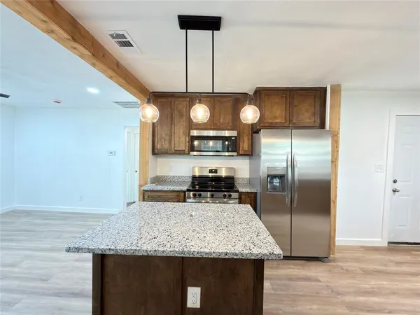 a kitchen with kitchen island a counter space a sink appliances and cabinets