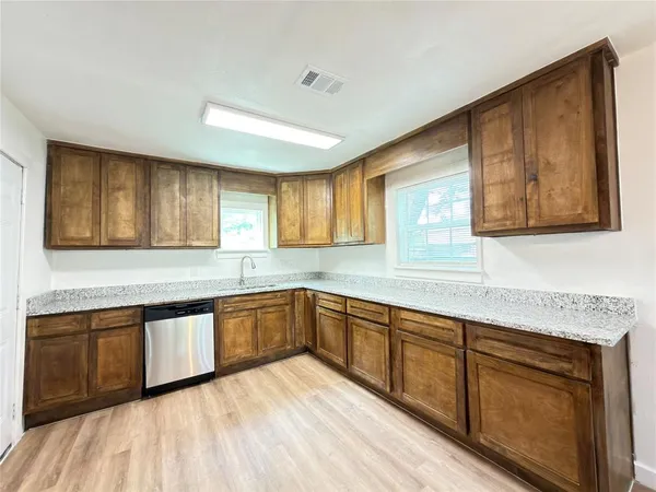 a view of a kitchen counter top space with stainless steel appliances wooden floor and cabinets