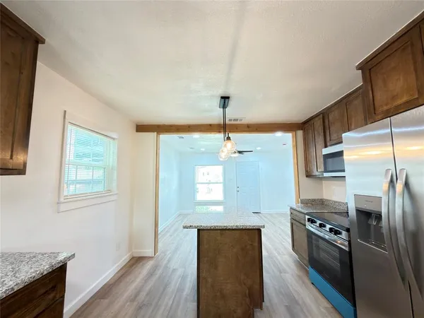a kitchen with stainless steel appliances granite countertop a refrigerator a stove and a wooden floors