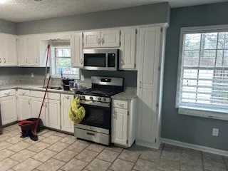 a kitchen with white cabinets a sink and a stove