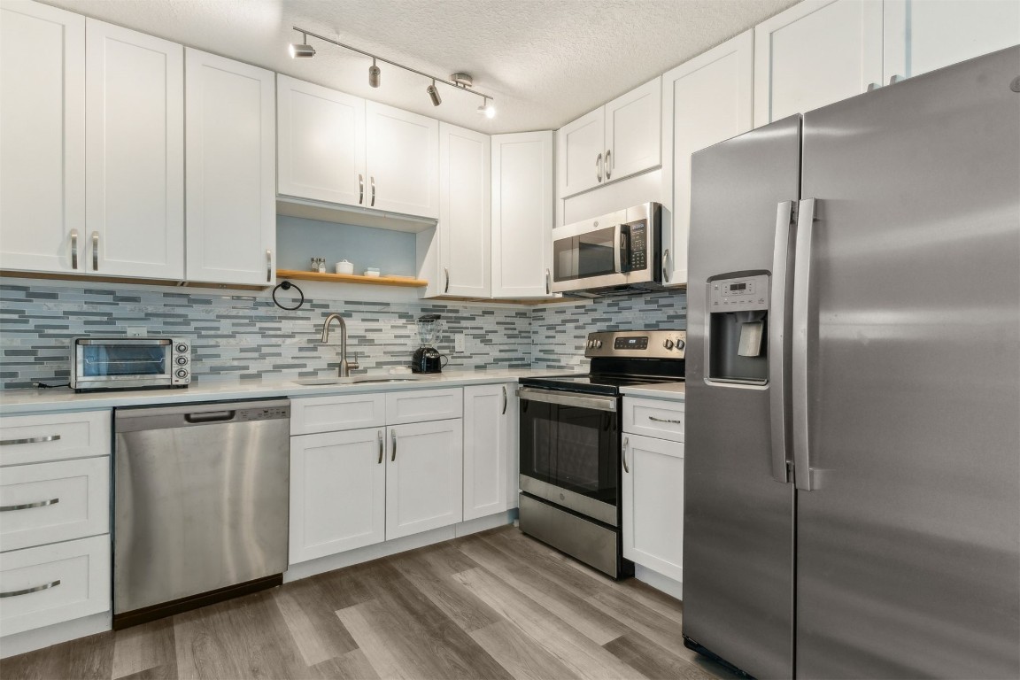914 Jasmine Street Fernandina Beach, FL 32034 - Photo 9 of 19 a kitchen with stainless steel appliances granite countertop a refrigerator a stove a sink and white cabinets