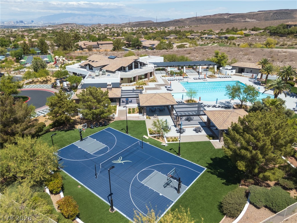 22 Douglas Grove Road Henderson, NV 89052 - Photo 11 of 72 An aerial perspective reveals a vibrant community with a sparkling pool, athletic courts, and scenic desert surroundings.