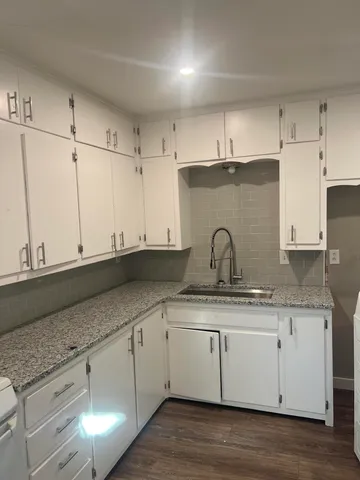 a white kitchen with sink and cabinets