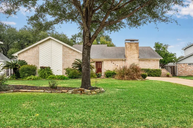 a front view of a house with a yard and tree