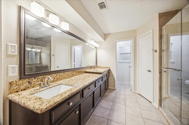 a bathroom with a granite countertop sink mirror and shower