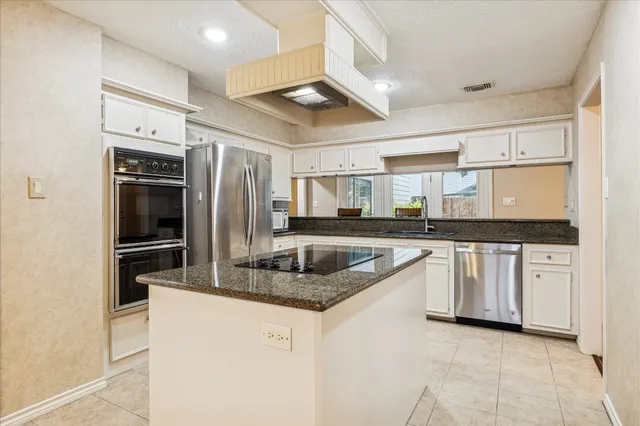 a kitchen with stainless steel appliances granite countertop a refrigerator a stove and a sink
