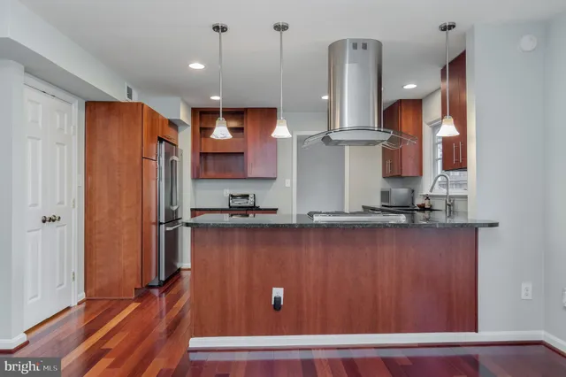 a kitchen with stainless steel appliances granite countertop wooden cabinets a stove a sink and a window