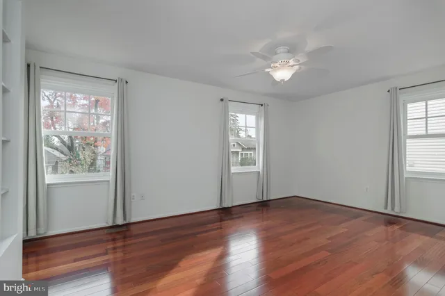 a view of an empty room with wooden floor & window
