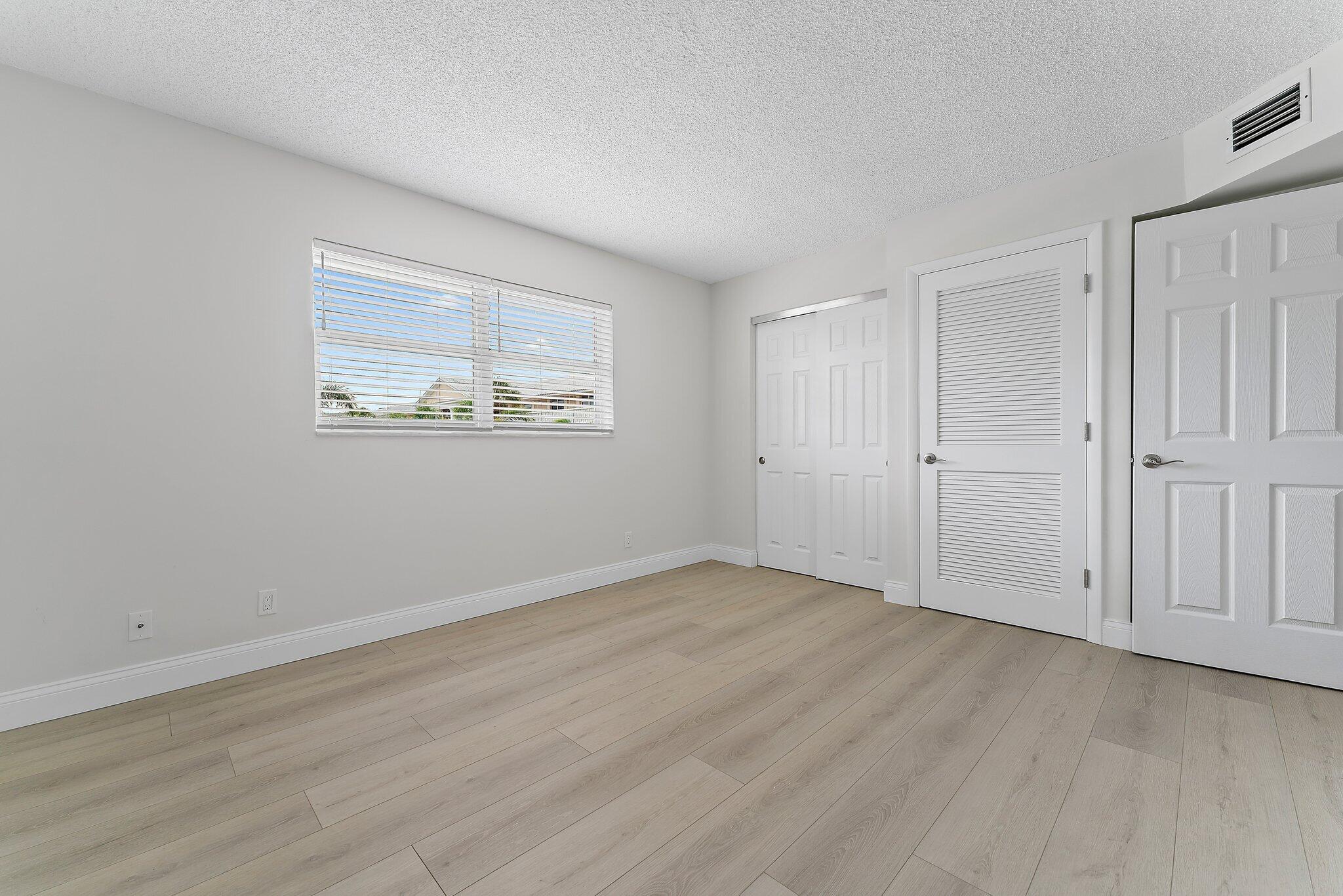 20 Celestial Way, Unit 215 Juno Beach, FL 33408 - Photo 18 of 25 an empty room with wooden floor and windows