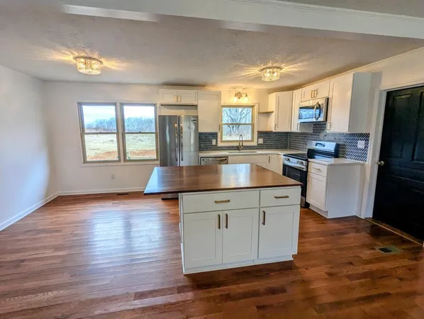 a kitchen with granite countertop a stove top oven a sink dishwasher a refrigerator and white cabinets with wooden floor