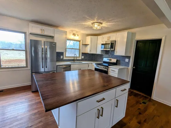 a kitchen with stainless steel appliances granite countertop a sink a stove and refrigerator