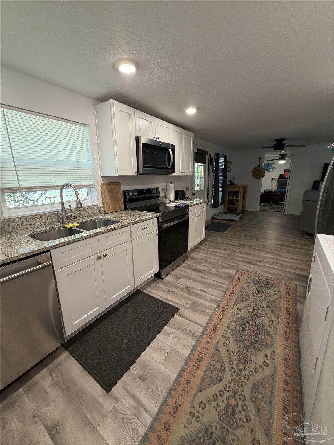 4532 Limit Street Milton, FL 32583 - Photo 8 of 18 a kitchen with stainless steel appliances granite countertop a sink dishwasher stove top oven and cabinets with wooden floor