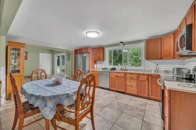 a kitchen with granite countertop wooden cabinets a stove a sink a dining table and chairs