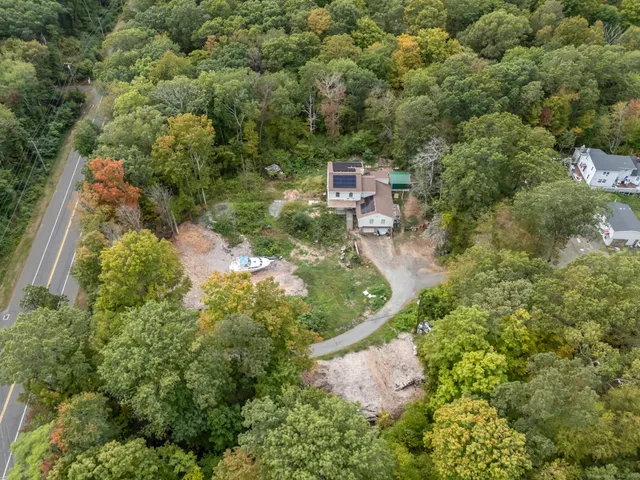 an aerial view of residential house with outdoor space and trees all around