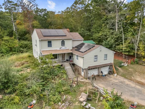 a view of a white house with a small yard and sitting area