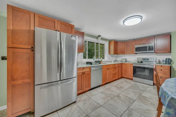 a kitchen with granite countertop wooden cabinets a stove a sink a dining table and chairs