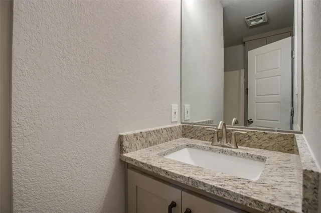 a bathroom with a granite countertop sink and a mirror