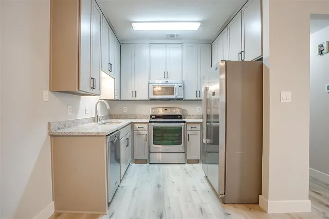 a kitchen with stainless steel appliances granite countertop a refrigerator and a stove top oven