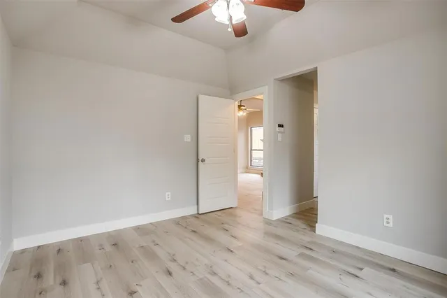 an empty room with wooden floor and chandelier fan