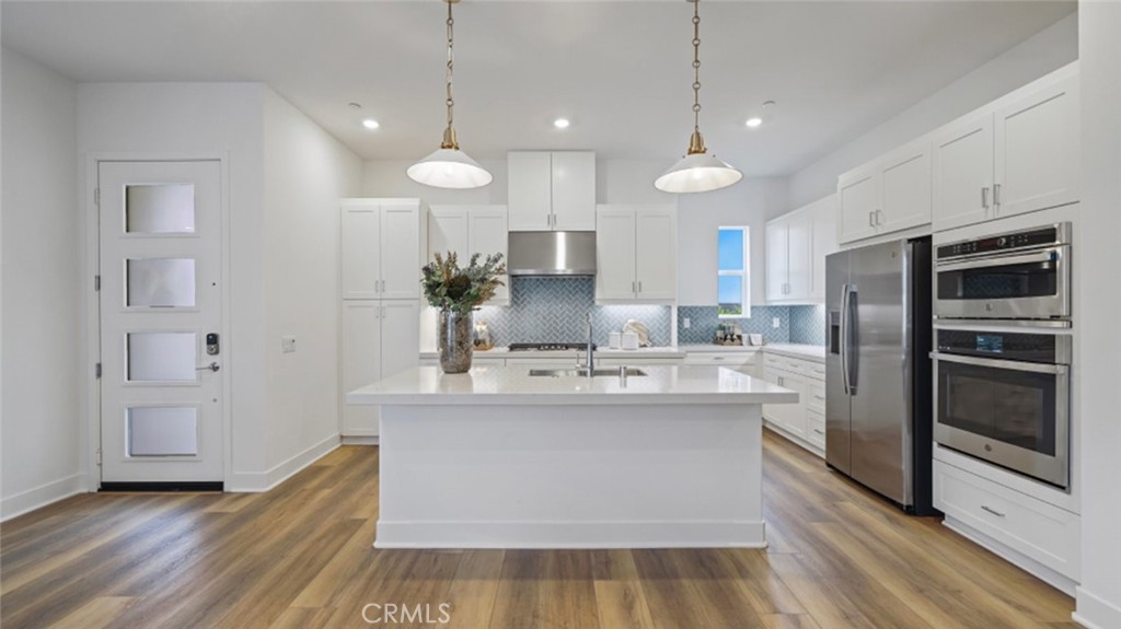 a view of a kitchen with kitchen island a sink stainless steel appliances and cabinets