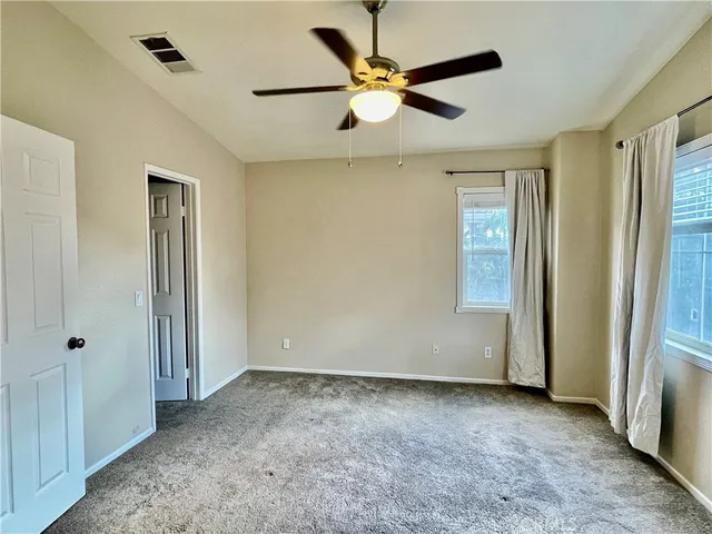 an empty room with closet and a ceiling fan